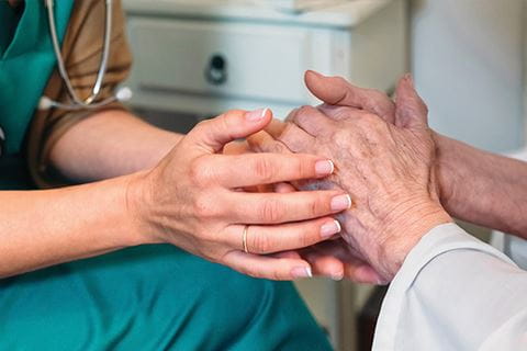 a nurse holds a patient's hands