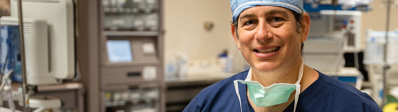 Dr. Jason Newman stands in an operating room wearing scrubs