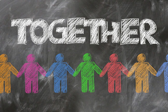 the word together written on a chalk board with multicolored stick figures holding hands below