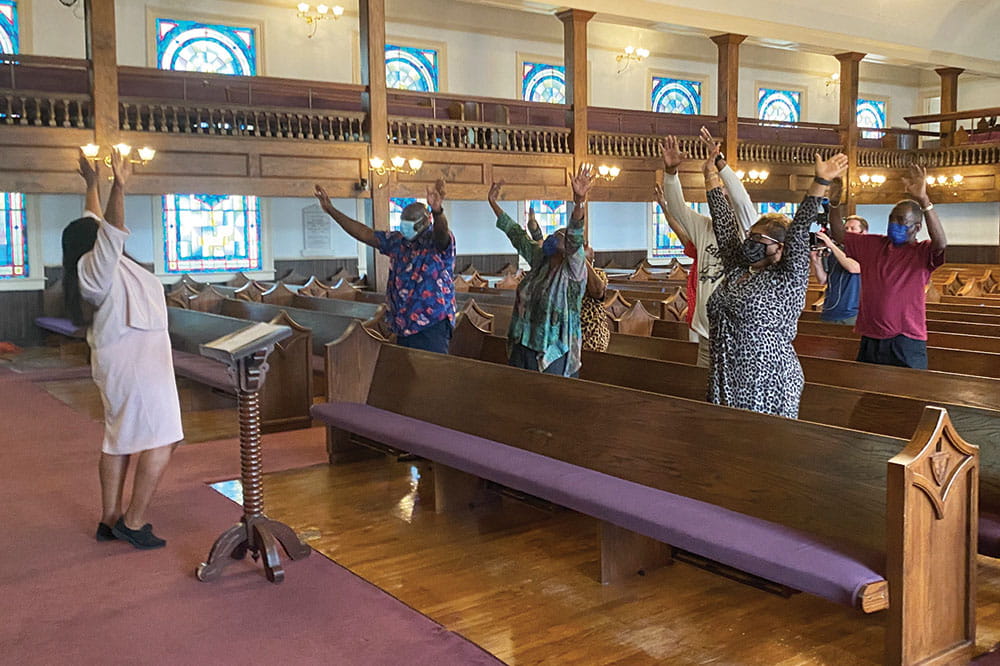 Dr. Marvella Ford leads a community group through fitness exercises in a church