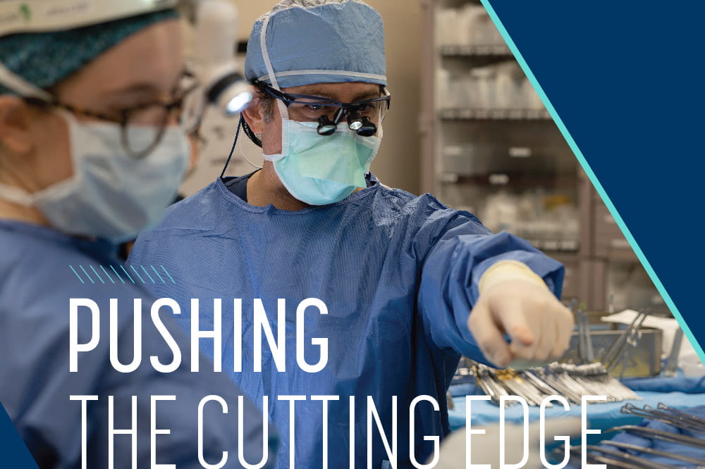 the words pushing the cutting edge over a photo of a man in surgical scrubs and mask pointing in an operating room while a woman dressed the same looks where he's pointing
