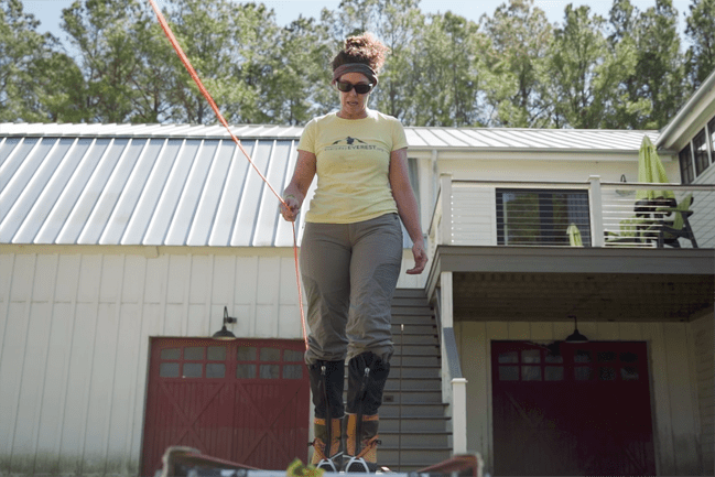 screenshot of Cokie Cox walking on a ladder while holding onto a rope
