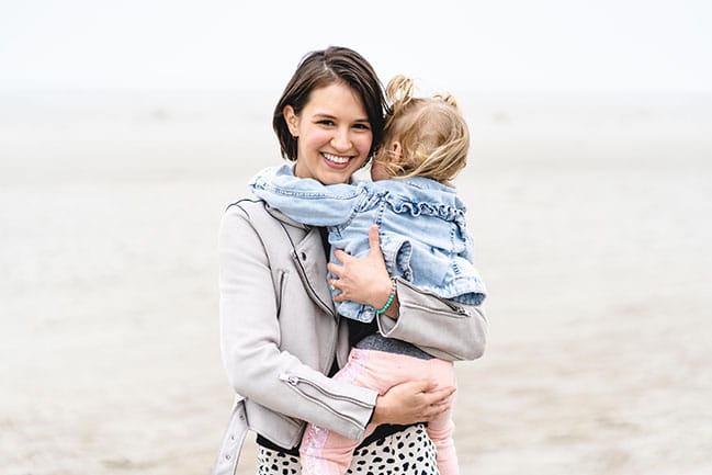 Liza Patterson holds her daughter in her arms on the beach