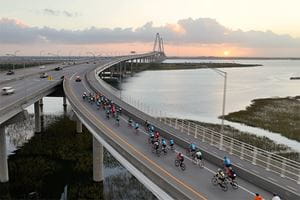 lowvelo cyclists ride onto the Ravenel Bridge as the sun rises in the background