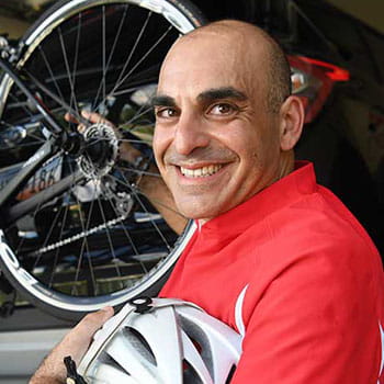 Nick Charalambous stands next to his bike holding a bike helmet