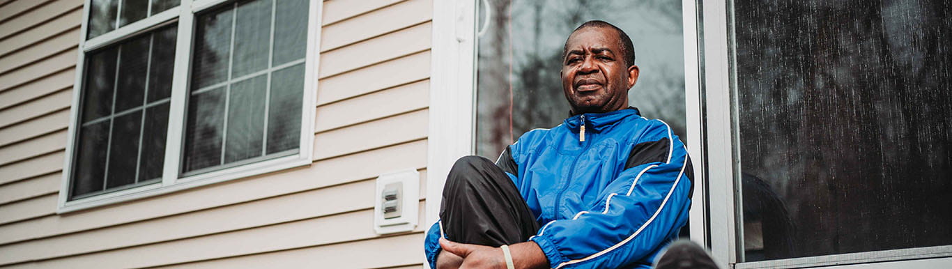 Lee Moultrie sits in front of his house with his hands clasped in front of his knee