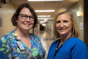 two radiation oncology nurses stand in hallway