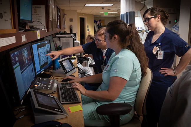 three radiation oncology team members look at computer screens