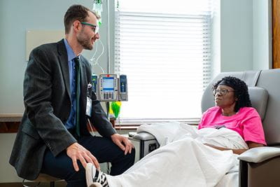 a doctor talking to a patient sitting in an infusion chair