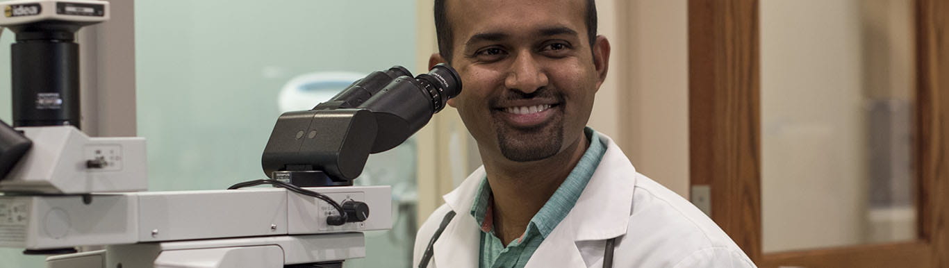 Dr. Amarendra Neppalli sits at a microscope