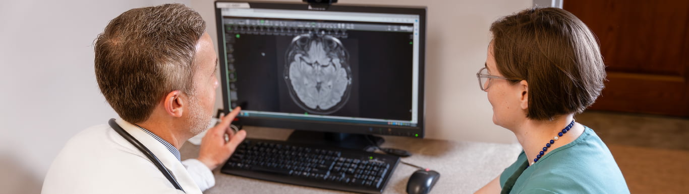 two neuro-oncologists look at a brain scan on a computer screen