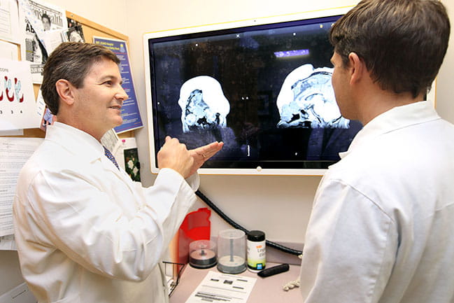 Dr. Rodney Schlosser looks at video screen showing patient scans with a colleague
