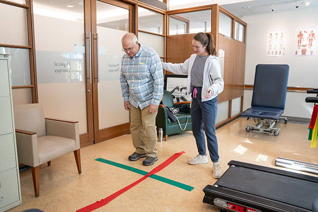 an occupational therapist helps a patient with a balance exercise