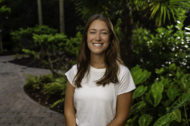 a smiling occupational therapist stands in a garden