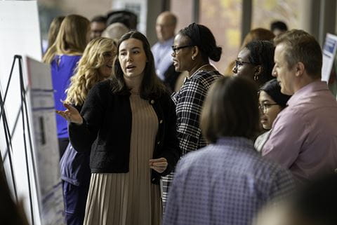 people gather around posters in a bustling hall at the Medical University of South Carolina