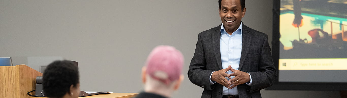 a professor talks at the front of a classroom