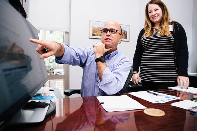 matt carpenter points at a computer screen while jen dahne looks on