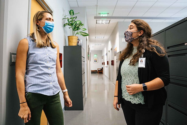 two people talk in an office hallway