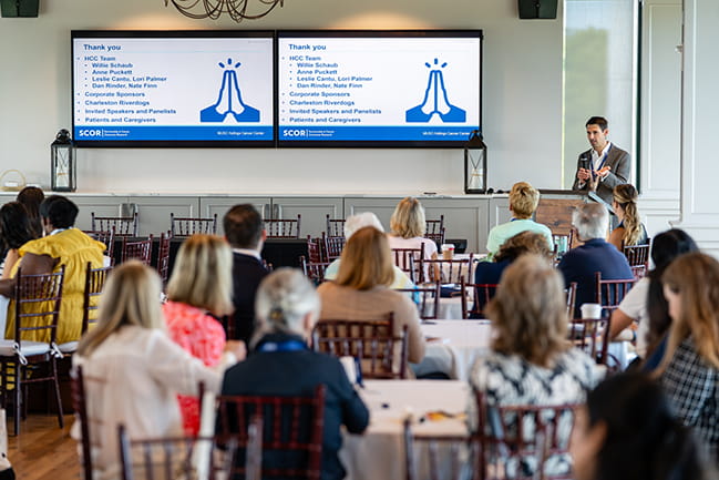 Dr. Evan Grayboyes speaking in front of a room full of people