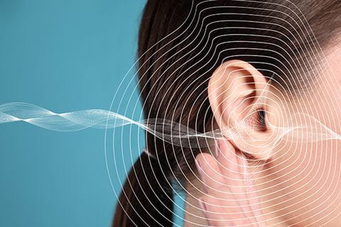 young woman holds her hand to her ear with sound waves overlaid on top
