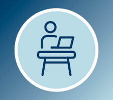 icon showing person using a laptop computer at a desk