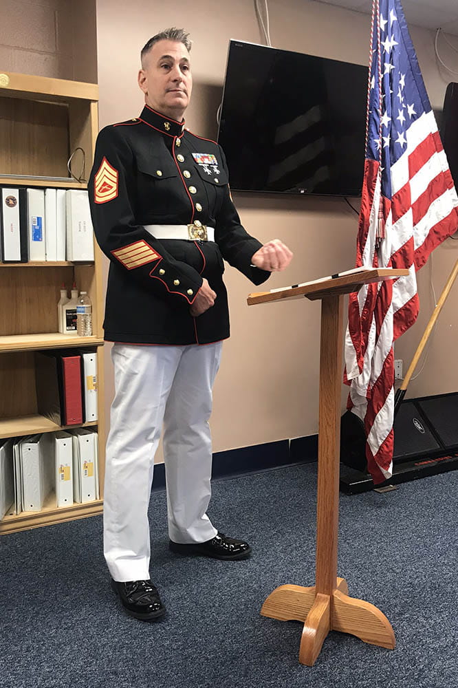 A man in a military outfit stand at podium. 