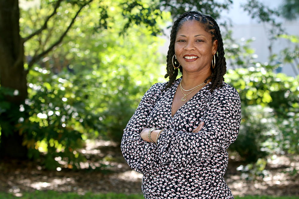 Chanita Hughes-Halbert stands outside under a tree