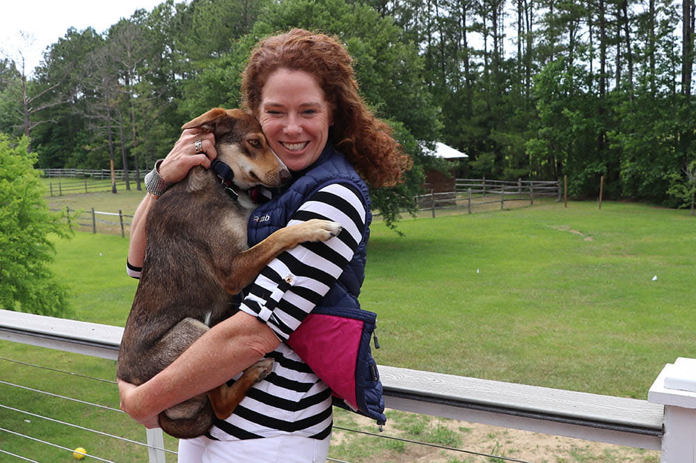 Cokie Berenyi holds her dog on the deck at her home