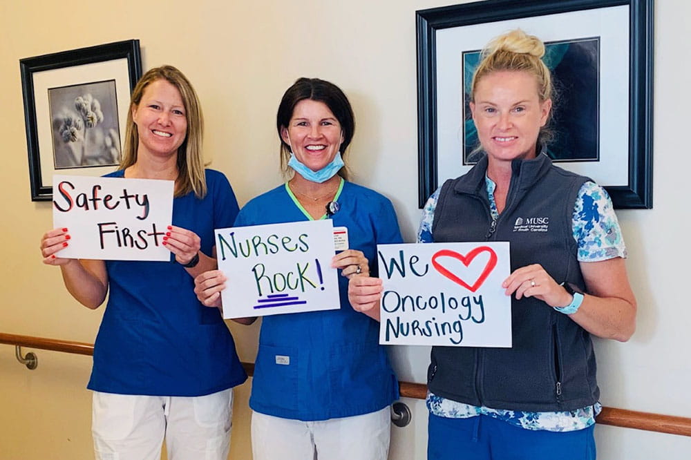 Nurses hold up signs that say safety first, nurses rock and we love oncology nursing