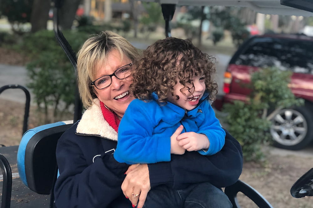 A woman holding a child while in a golf cart. 