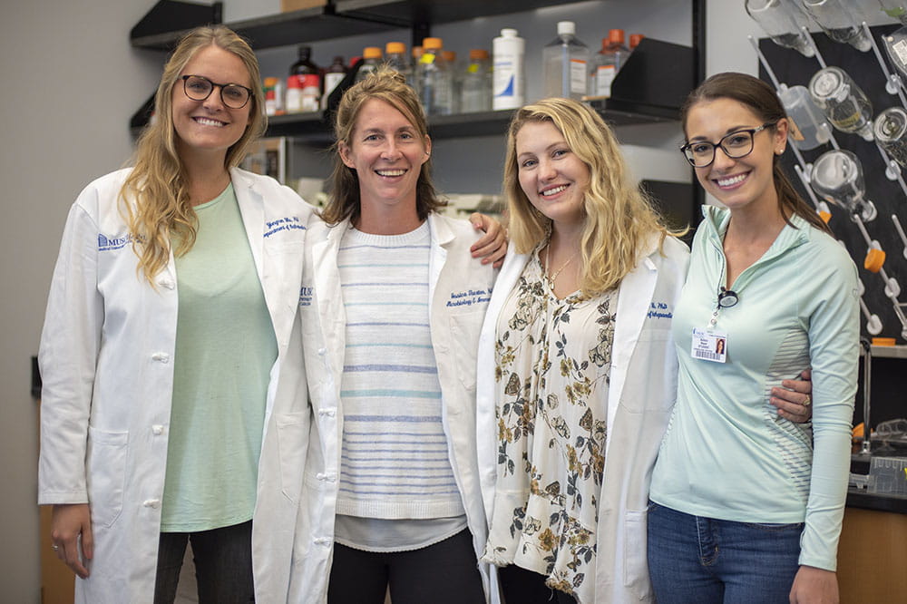 Katie Hurst, Jessica Thaxton, Kiley Lawrency and Ashton Basar stand together in the lab
