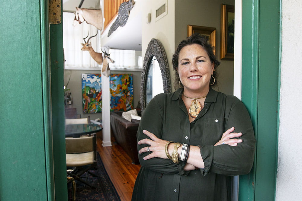 Suzette Bussey stands in a doorway in her house with art and furniture behind her