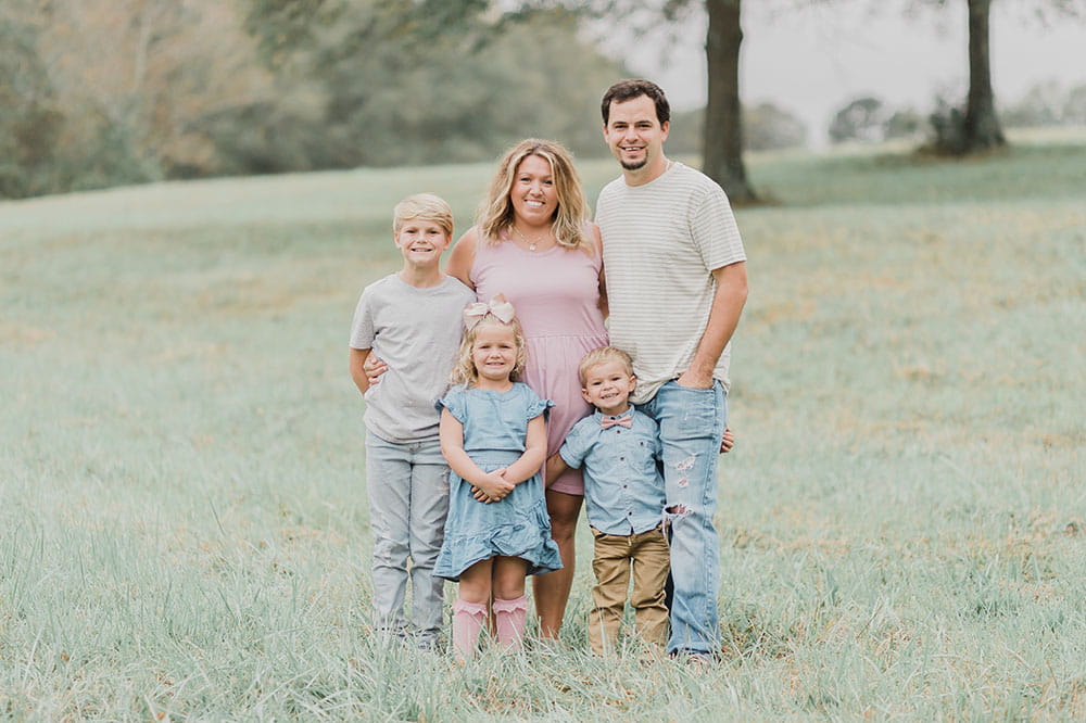 Halea Wylie stands in a field of grass with her fiancee and their three children