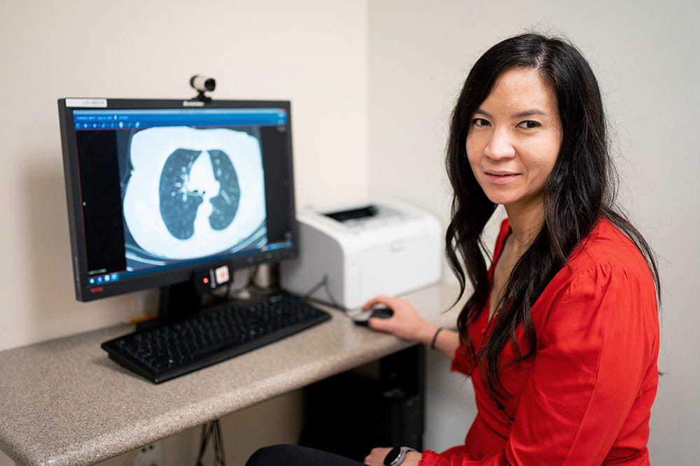 Dr. Nichole Tanner sits in front of a computer showing a lung scan