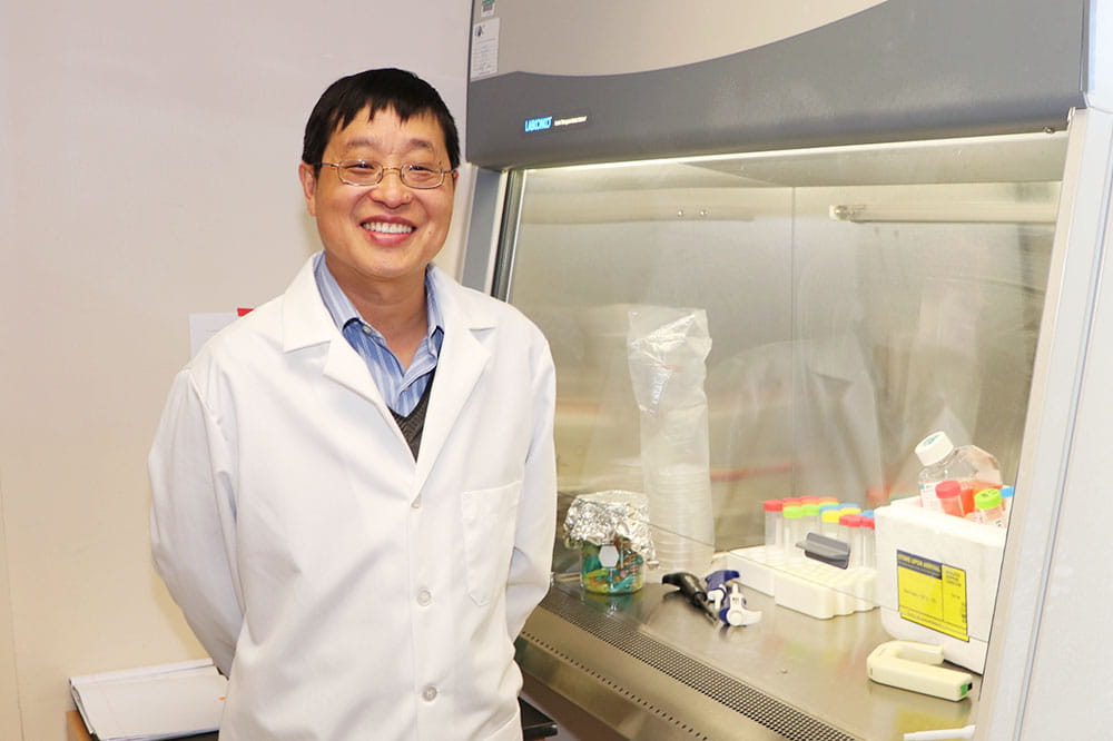 Dr. Xue-Zhong Yu stands next to equipment in his lab