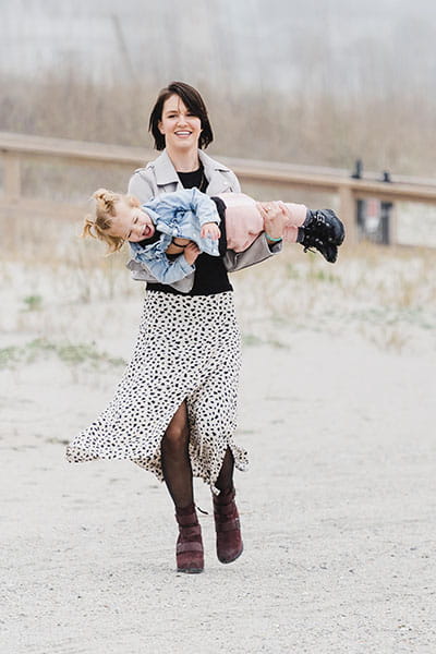 Liza Patterson carries her daughter on the beach