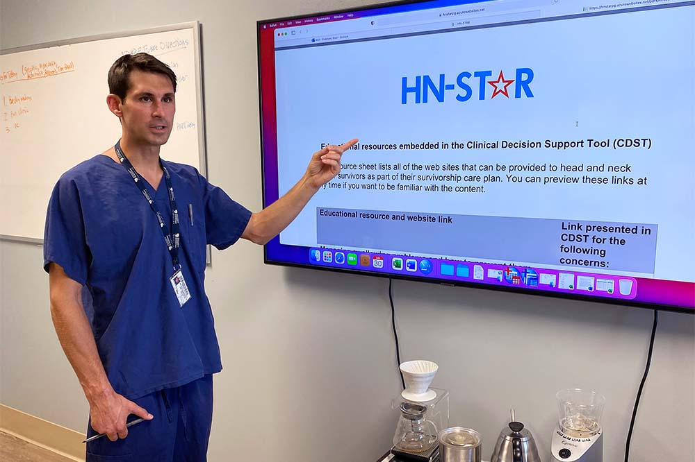 Dr. Evan Graboyes points at a TV screen showing HN Star information
