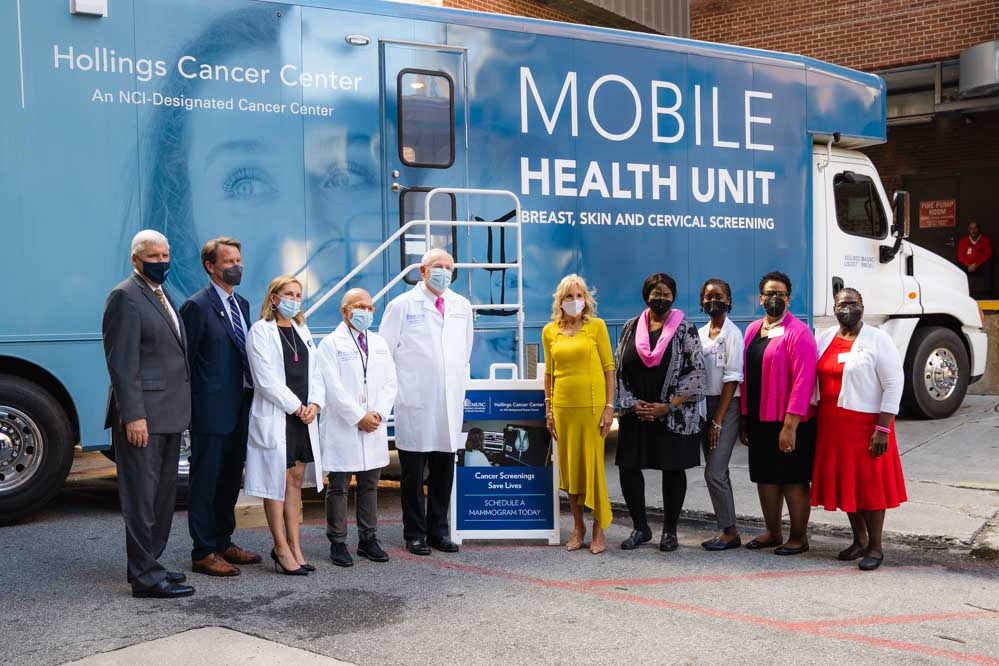 First lady Dr. Jill Biden stands in front of the Hollings mobile health unit with a group of administrators, doctors, researchers and community partners