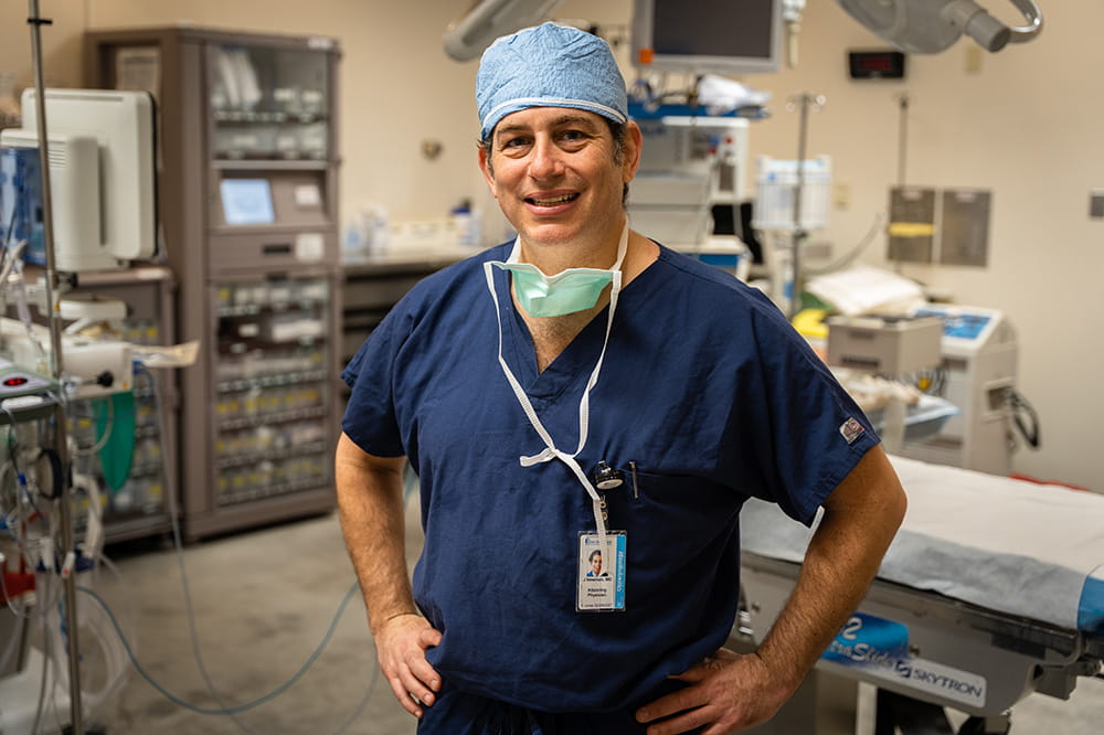 Dr. Jason Newman stands in an operating room wearing scrubs