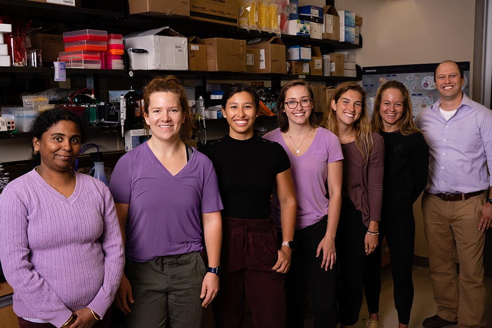 group photo in a lab with everyone wearing shades of purple