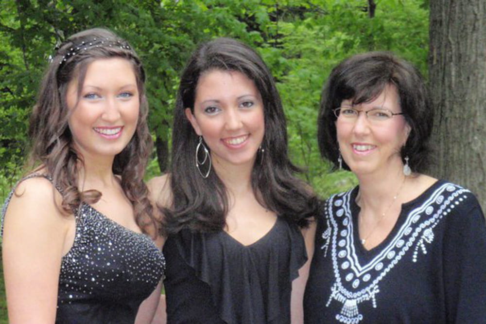 two young women in prom dresses pose with their mother