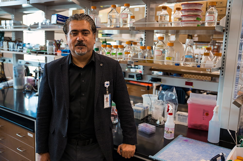 portrait of a man in dark shirt and sports jacket in a lab