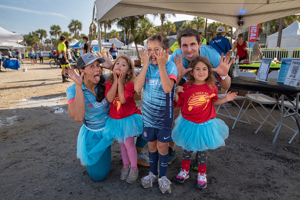 a family of five with the girls in tutus makes silly faces at the camera
