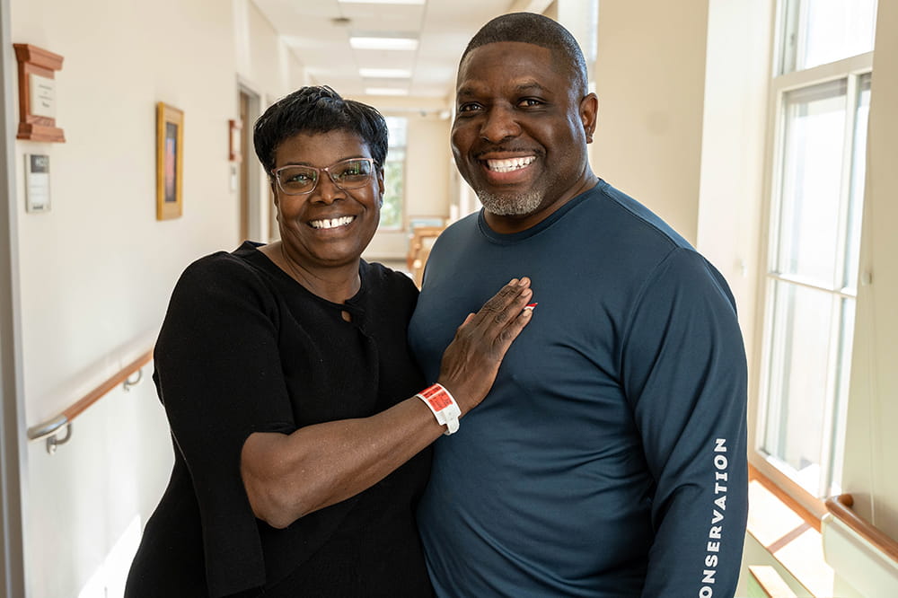a smiling couple pose in a cancer center hallway