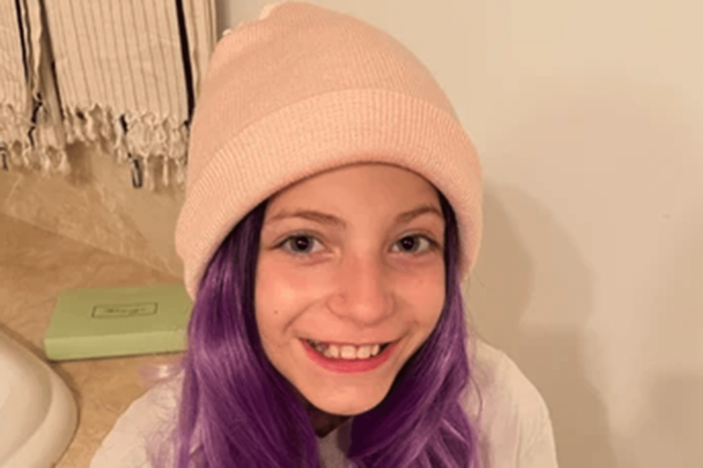 image of young girl with purple hair flowing from beneath knit cap