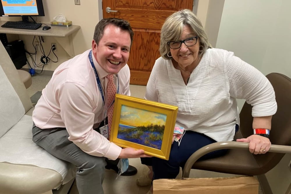 a doctor and patient pose in an exam room with a small framed artwork