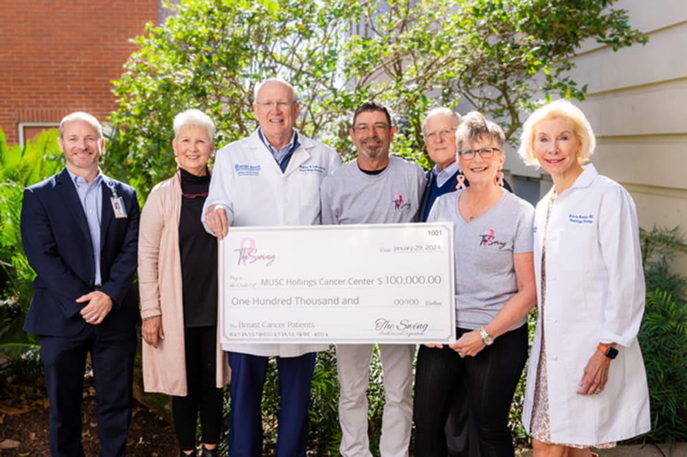 group photo of people in a garden setting with an oversized check 