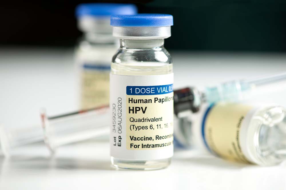 closeup of vials of HPV vaccine with a needle