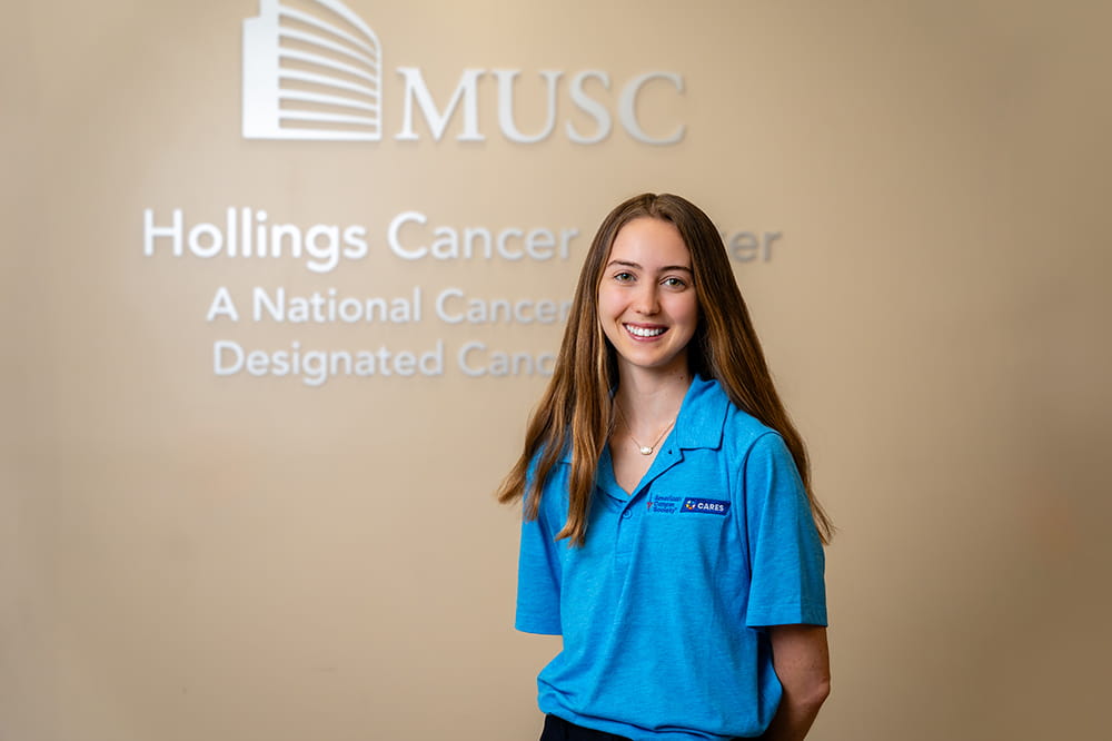 a young woman poses in front of the MUSC Hollings Cancer Center sign on the wall 