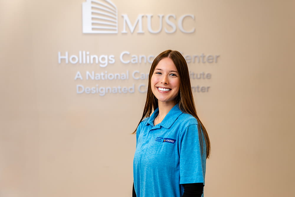 a young woman poses in front of the MUSC Hollings Cancer Center sign on the wall 